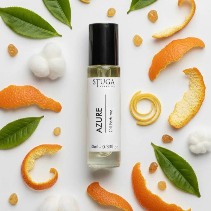 10ml Stuga Azure oil perfume with citrus peels, green leaves, and cotton balls on white background