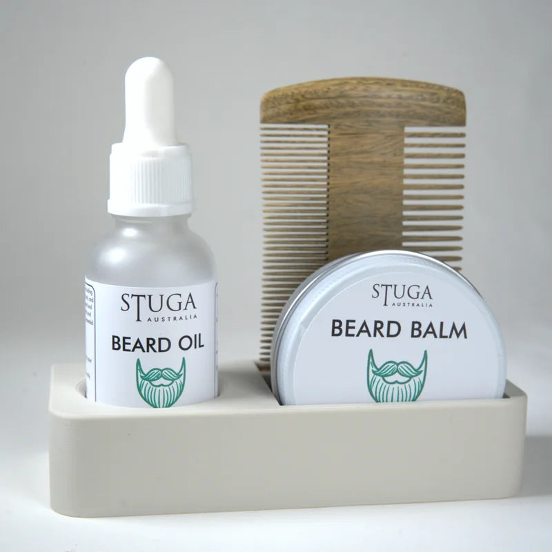 Stuga Australia beard oil and beard balm in white containers with green logo, accompanied by a wooden beard comb in a beige h