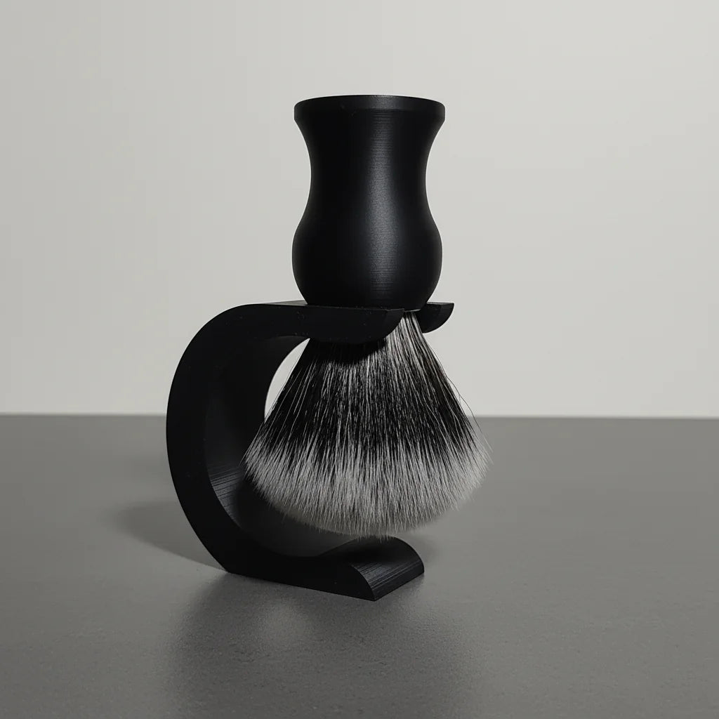 Black shaving brush with synthetic badger hair bristles, resting in a matching black stand on a grey surface.