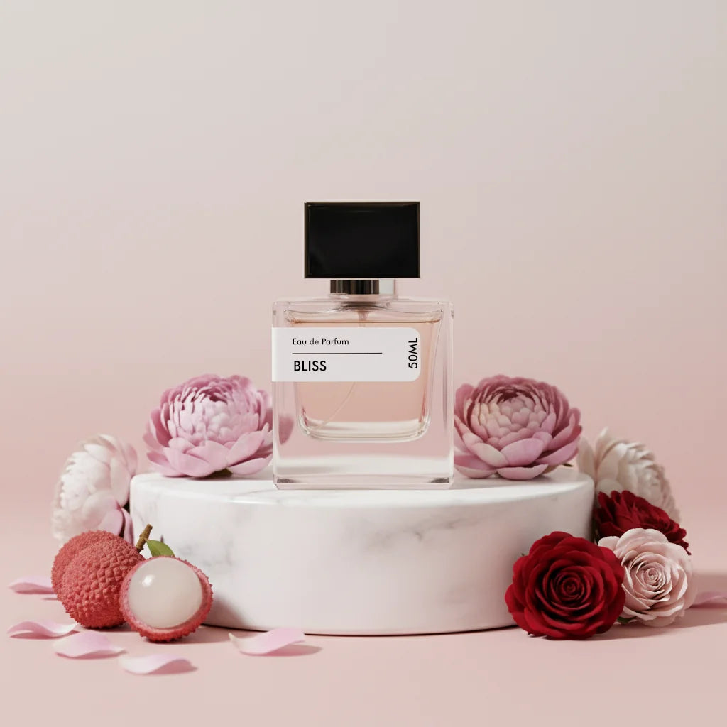 Bliss Eau de Parfum 50ml bottle with black cap, surrounded by pink and red roses, lychee fruit, and petals on a white marble