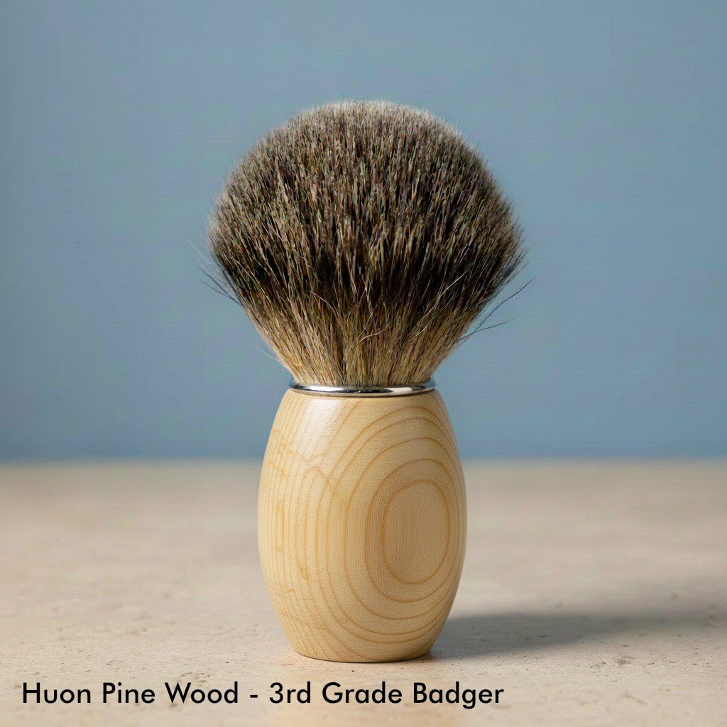 Close-up of a shaving brush with a light-colored huon pine wood handle and dark 3rd grade badger bristles.