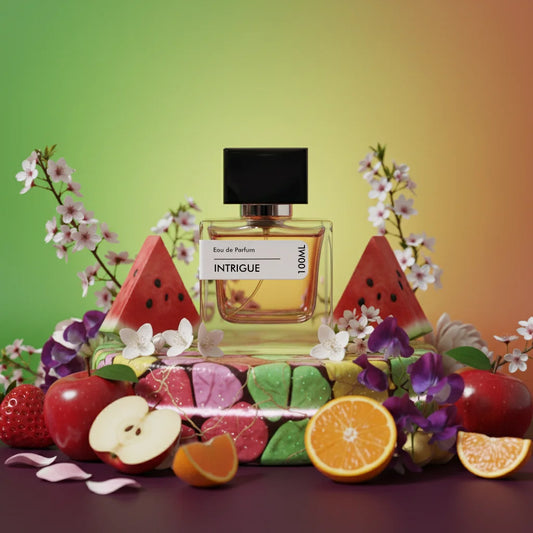 Intrigue Eau de Parfum 100ml bottle surrounded by fresh fruit slices, flowers, and colorful candies on a vibrant background.