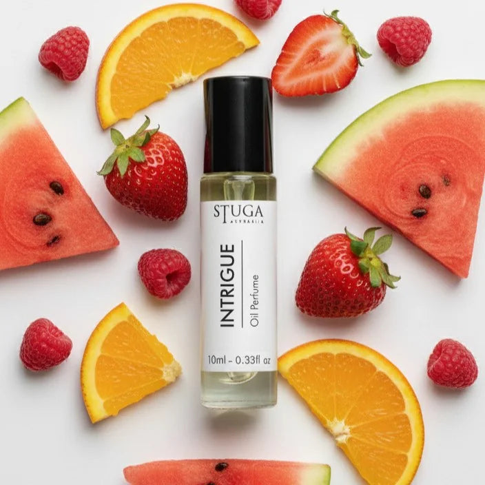 10ml Stuga Australia Intrigue oil perfume surrounded by fresh watermelon, orange, strawberry, and raspberry slices