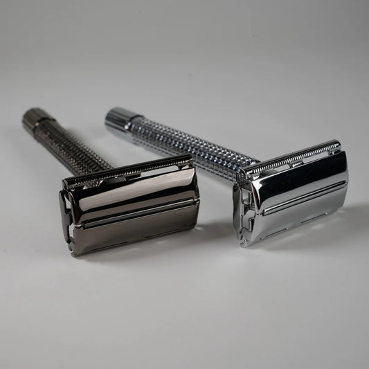 Two metal double edge safety razors with textured handles in silver and dark chrome finish for precise shaving
