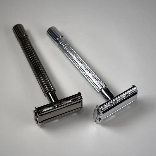 Two metal double edge safety razors with textured handles in silver and dark chrome finish for precise shaving