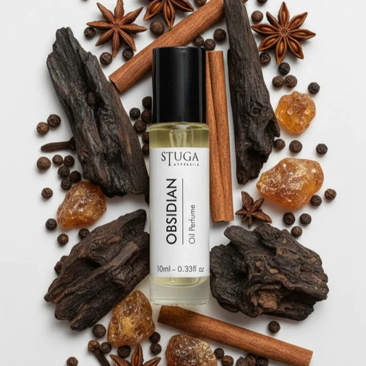 10ml Stuga Obsidian oil perfume bottle surrounded by cinnamon sticks, star anise, amber resin, and dark wood pieces