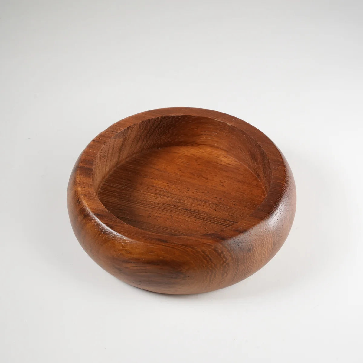 Round wooden serving bowl made of polished dark brown wood with smooth curved edges