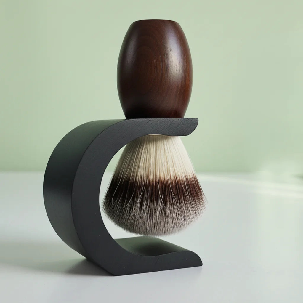 Dark wood shaving brush with badger hair bristles on a black curved stand, against a light green background.
