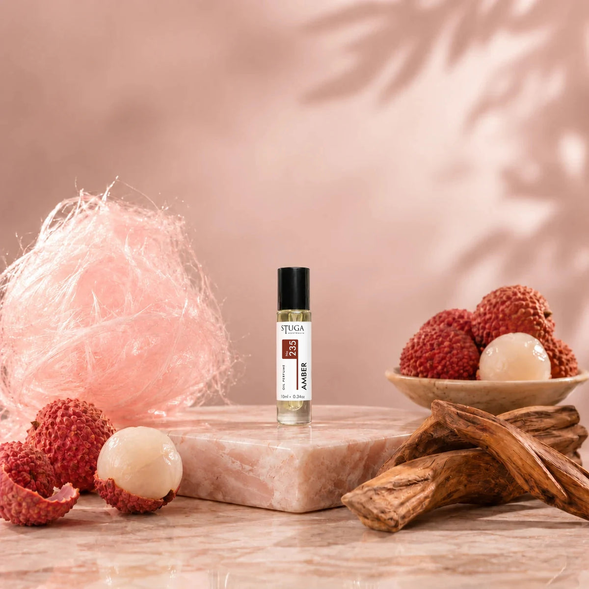 Stuga Amber No. 235 amber oil perfume, 10ml roll-on bottle on pink marble with spun sugar, lychees and amberwood.
