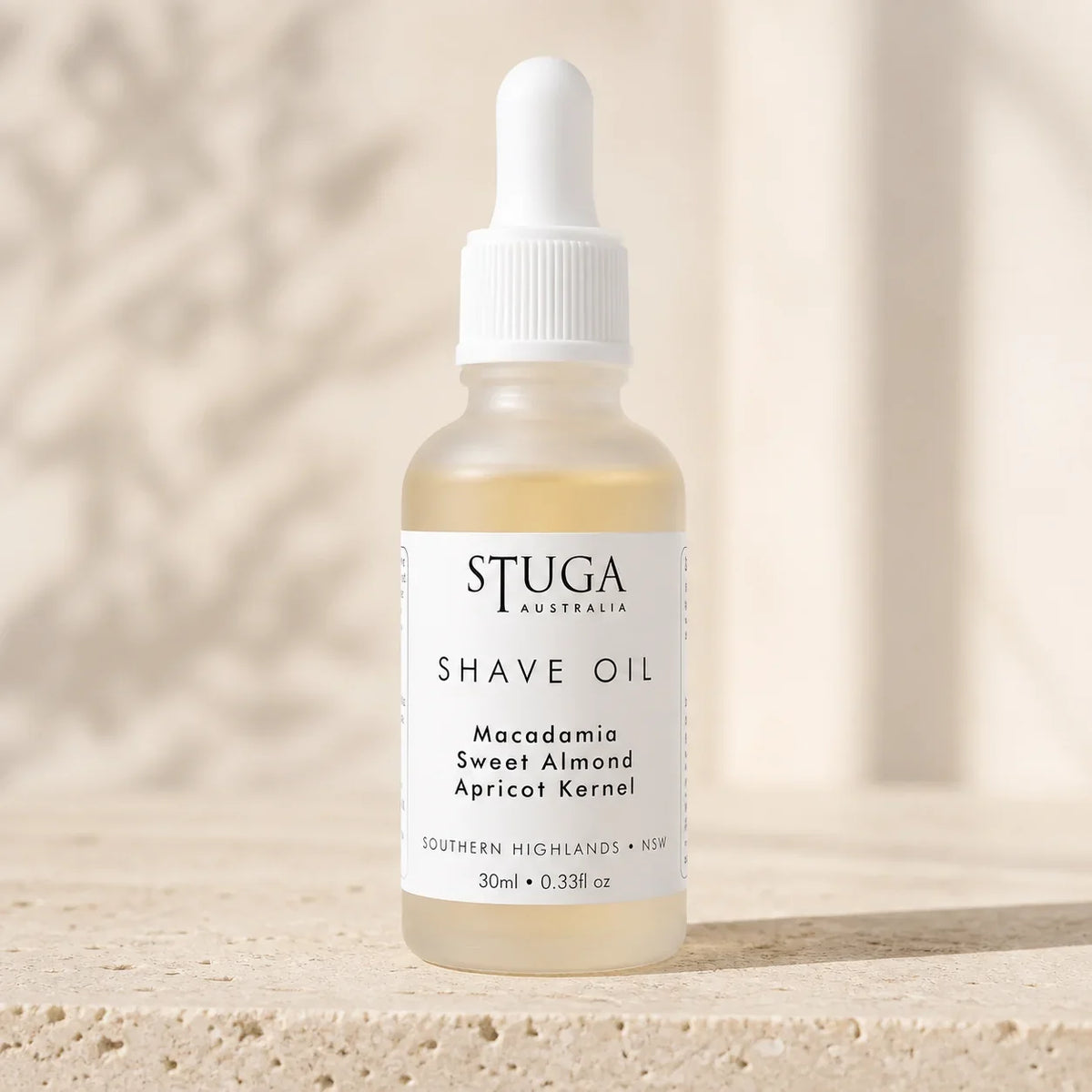30ml Stuga Australian shave oil in a frosted glass dropper bottle on warm stone