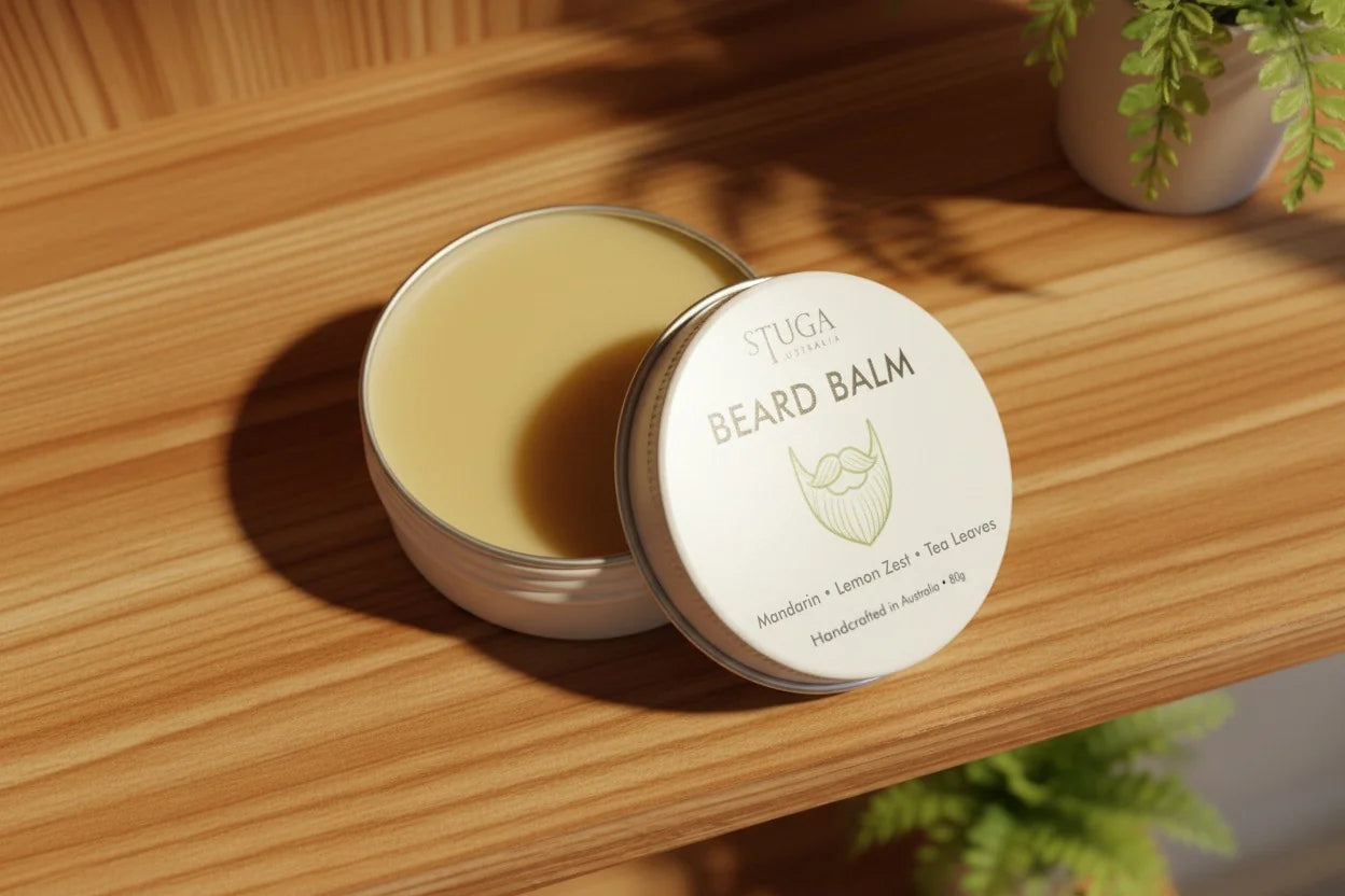 Stuga Australia beard balm with mandarin, lemon zest, and tea leaves in an open tin on a wooden shelf.