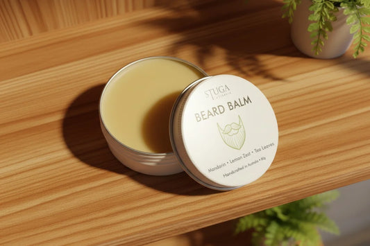 Stuga Australia beard balm with mandarin, lemon zest, and tea leaves in an open tin on a wooden shelf.
