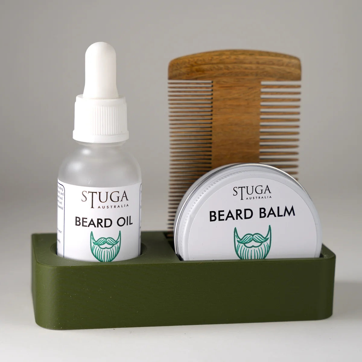 Stuga Australia beard oil and beard balm in white containers with green logo, wooden beard comb, all in green holder