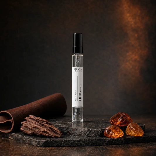 Stuga Oud No. 401 oud perfume, 10ml eau de parfum spray bottle on dark stone with rolled leather, oud wood chips and golden amber resin.