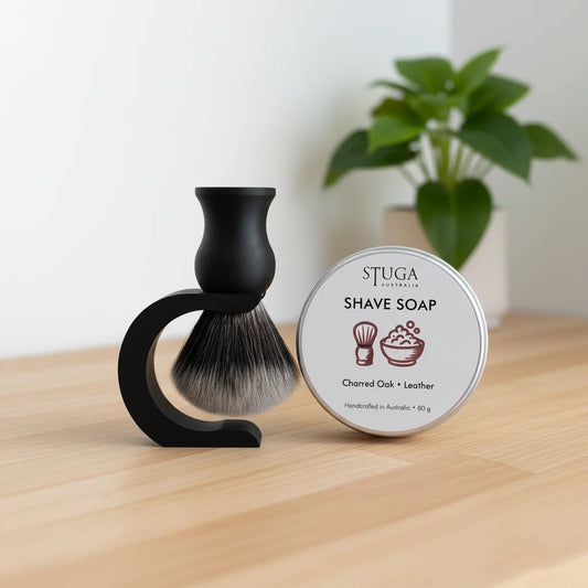 Stuga Australia shave soap in a tin, charred oak and leather scent, with a black shaving brush and stand.