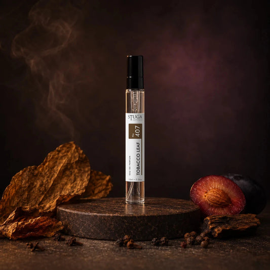 Stuga Tobacco Leaf No. 407 tobacco perfume, 10ml eau de parfum spray bottle on a dark stone plinth with dried tobacco leaves, a spiced plum and drifting smoke.