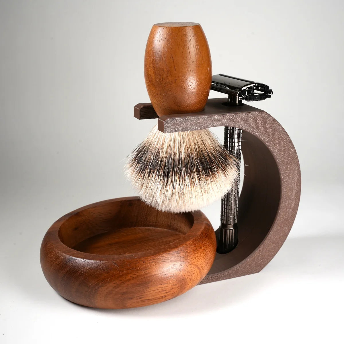 Wooden shaving brush with natural bristles, metal razor, and wooden bowl on a brown stand for traditional wet shaving