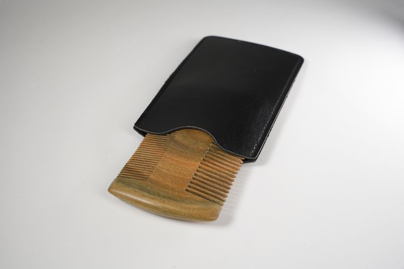 Wooden beard comb with fine and wide teeth in a black leather protective case for grooming