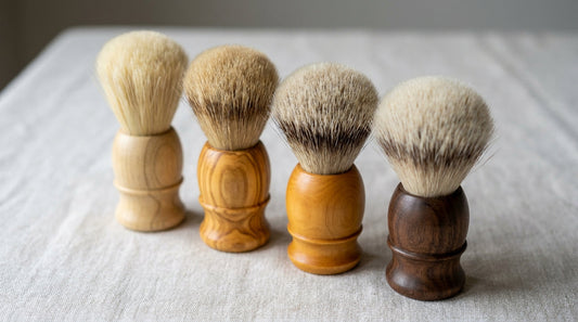 Four handmade shaving brushes in a row showing badger grades from pure to silvertip, each with a hand-turned timber handle