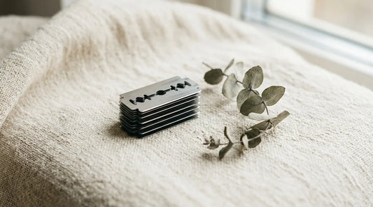 A stack of used double edge razor blades on linen — the disposal question every safety razor shaver faces