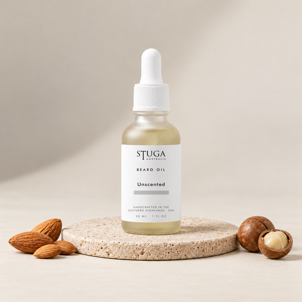 Stuga Beard Oil in Unscented — pale golden oil in a frosted glass dropper bottle on a travertine stone disc with sweet almonds and macadamia nuts. Fragrance-free beard oil made fresh to order with Australian sweet almond, macadamia and apricot kernel oils, handcrafted in the Southern Highlands, NSW Australia.