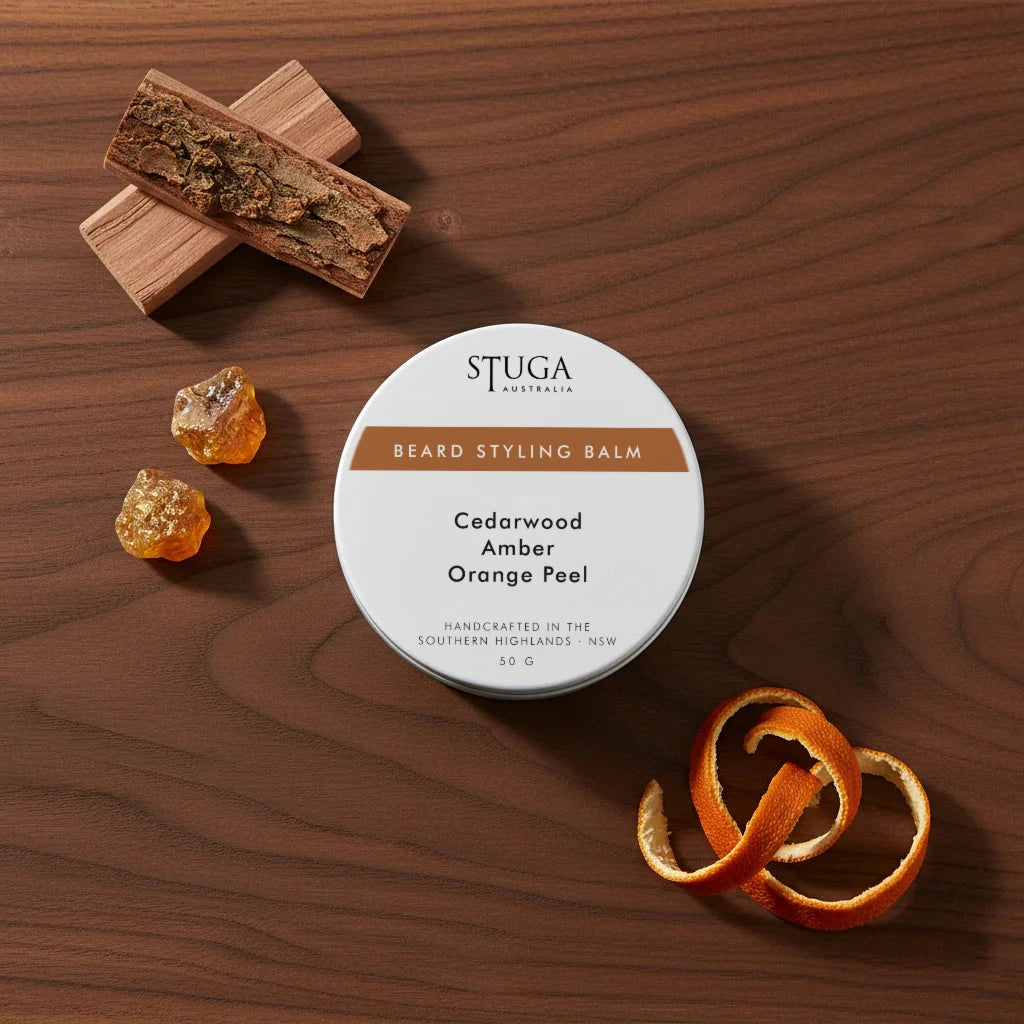 Stuga Australia Beard Styling Balm in 50g tin, scented with cedarwood, amber, and orange peel, on dark wood surface