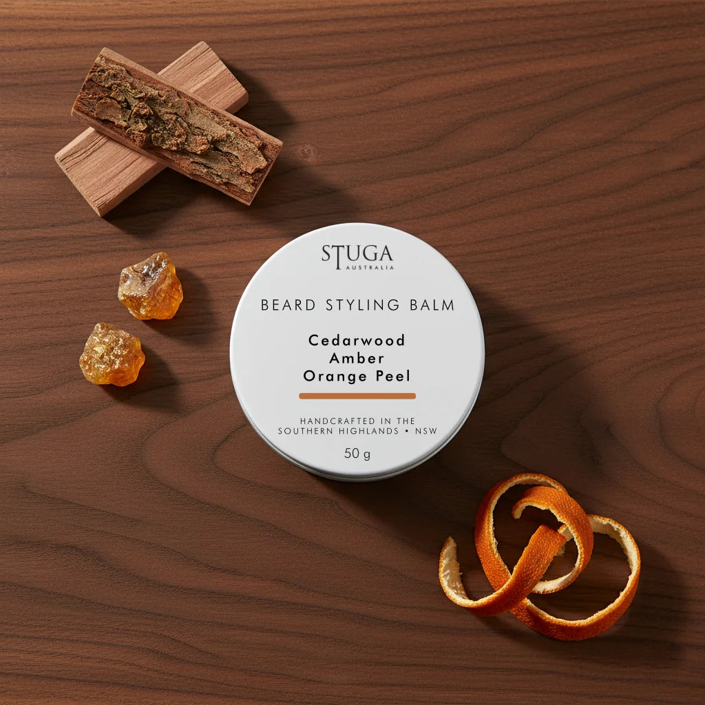 Stuga Australia Beard Styling Balm in 50g tin, scented with cedarwood, amber, and orange peel, on dark wood surface