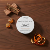 Stuga Australia Beard Styling Balm in 50g tin, scented with cedarwood, amber, and orange peel, on dark wood surface