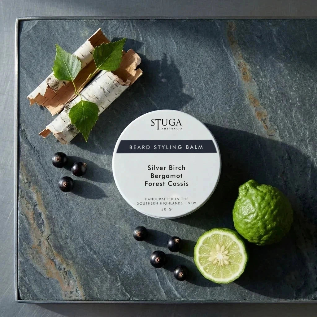 Stuga Beard Styling Balm in Silver Birch, Bergamot and Forest Cassis — 50g white tin on a slate slab with birch bark, fresh birch leaves, blackcurrants and cut bergamot. Natural hold beard balm handcrafted in the Southern Highlands, NSW Australia.