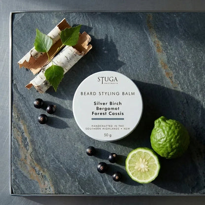 Stuga Beard Styling Balm in Silver Birch, Bergamot and Forest Cassis — 50g white tin on a slate slab with birch bark, fresh birch leaves, blackcurrants and cut bergamot. Natural hold beard balm handcrafted in the Southern Highlands, NSW Australia.