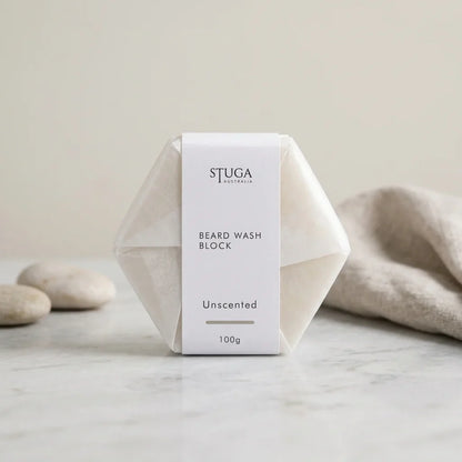 Stuga Australia Beard Wash Block, unscented natural shampoo bar, 100g, with smooth pebbles and a linen towel on a stone benchtop.