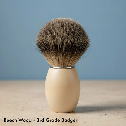 Close-up of a shaving brush with a light-colored, smooth beech wood handle and soft, dark brown 3rd grade badger bristles.