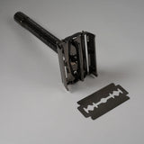 Black metal safety razor with textured handle and detachable double-edge blade for precise shaving
