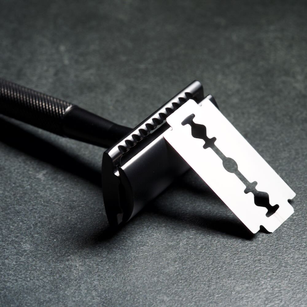 WÖLFE 97 three-piece DE safety razor shown with handle, base plate and cap, in matte black.