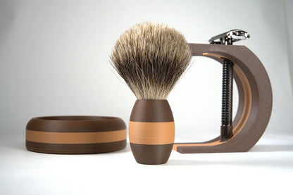 Brown and tan striped shaving brush with soft bristles next to matching shaving bowl and clamp-style stand