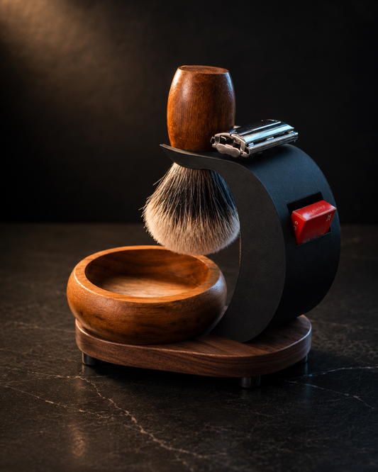 Stuga Complete Shaving Kit shown from the side — badger brush, safety razor, blade sampler, timber bowl and matte black stand on a timber base
