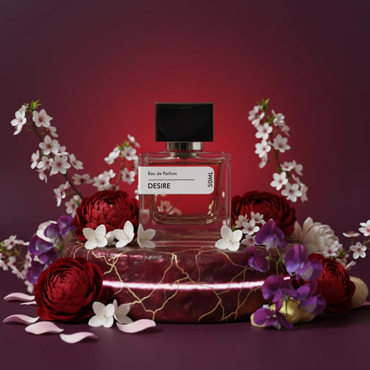 Desire Eau de Parfum 50ml bottle with black cap, surrounded by red peonies, white cherry blossoms, and purple flowers on a cr