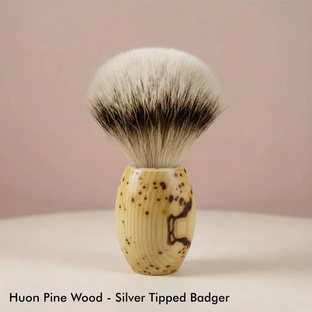 Huon pine wood handle shaving brush with silver tipped badger bristles, light wood grain with dark flecks, for wet shaving.