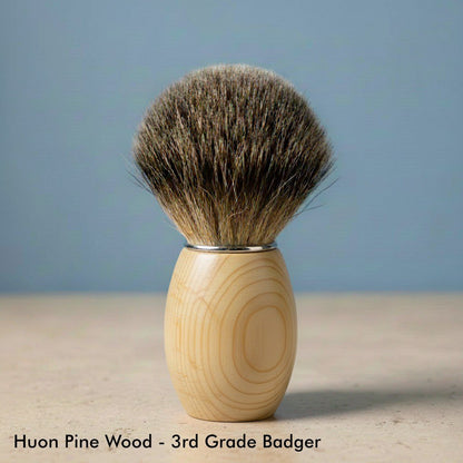 Close-up of a shaving brush with a light-colored huon pine wood handle and dark 3rd grade badger bristles.