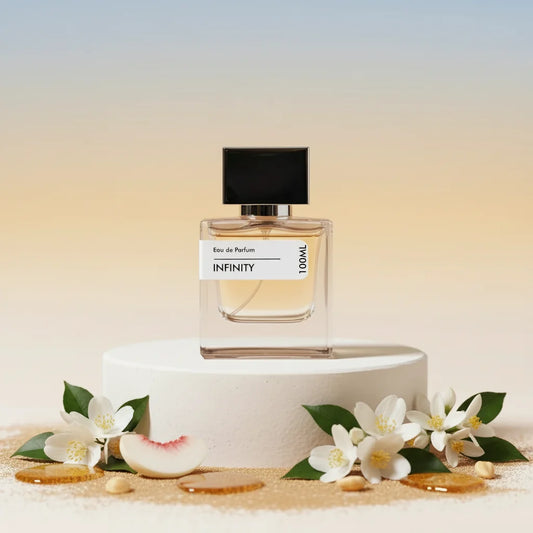 Infinity Eau de Parfum, 100ml, clear glass bottle with black cap, surrounded by white jasmine flowers, peach slice, and gold 