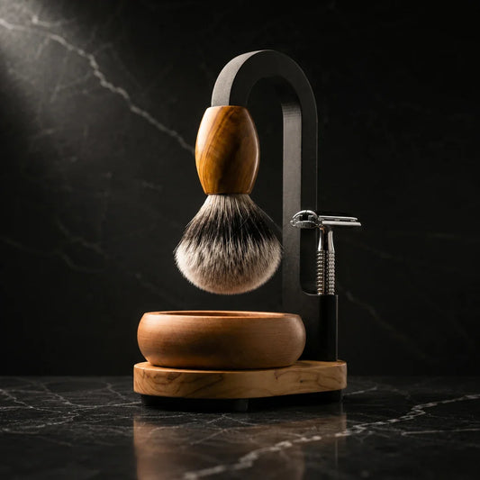 Luxury Magic Shaving Kit — silver tip badger brush with olive wood handle suspended from black arch stand, handturned timber bowl and safety razor on dark marble