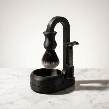 Matte black shaving set with safety razor, shaving brush, and arched stand with bowl on marble surface