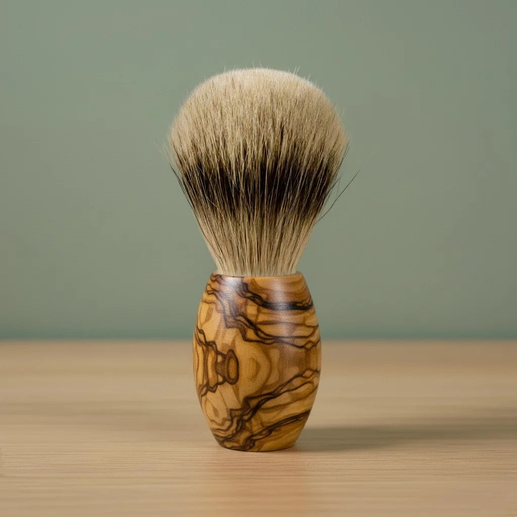 2nd grade badger bristle shaving brush with a beautifully grained olive wood handle, standing on a wooden surface.