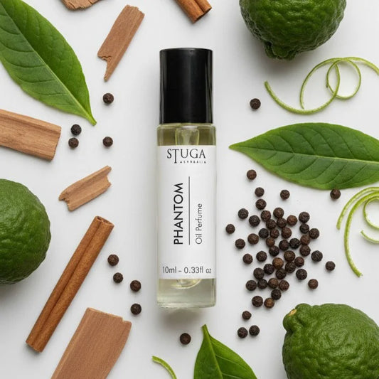 10ml Phantom oil perfume roll-on bottle surrounded by fresh bergamot, cinnamon sticks, black peppercorns, and green leaves