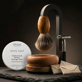 Premium Magic Shaving Kit — badger brush with olive wood handle suspended from black arch stand, STUGA shave soap tin, handturned timber bowl, safety razor and wrapped blades on slate