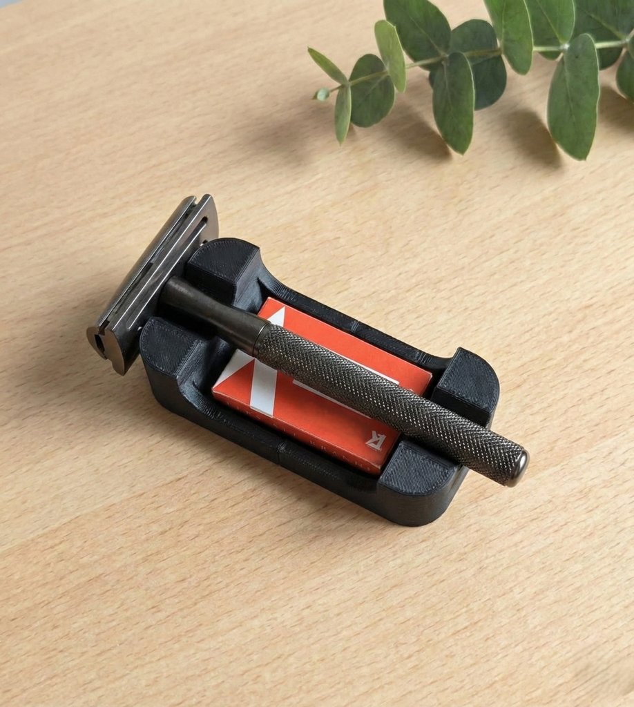 Black razor rest with orange blade storage compartment holding a chrome safety razor on wood surface