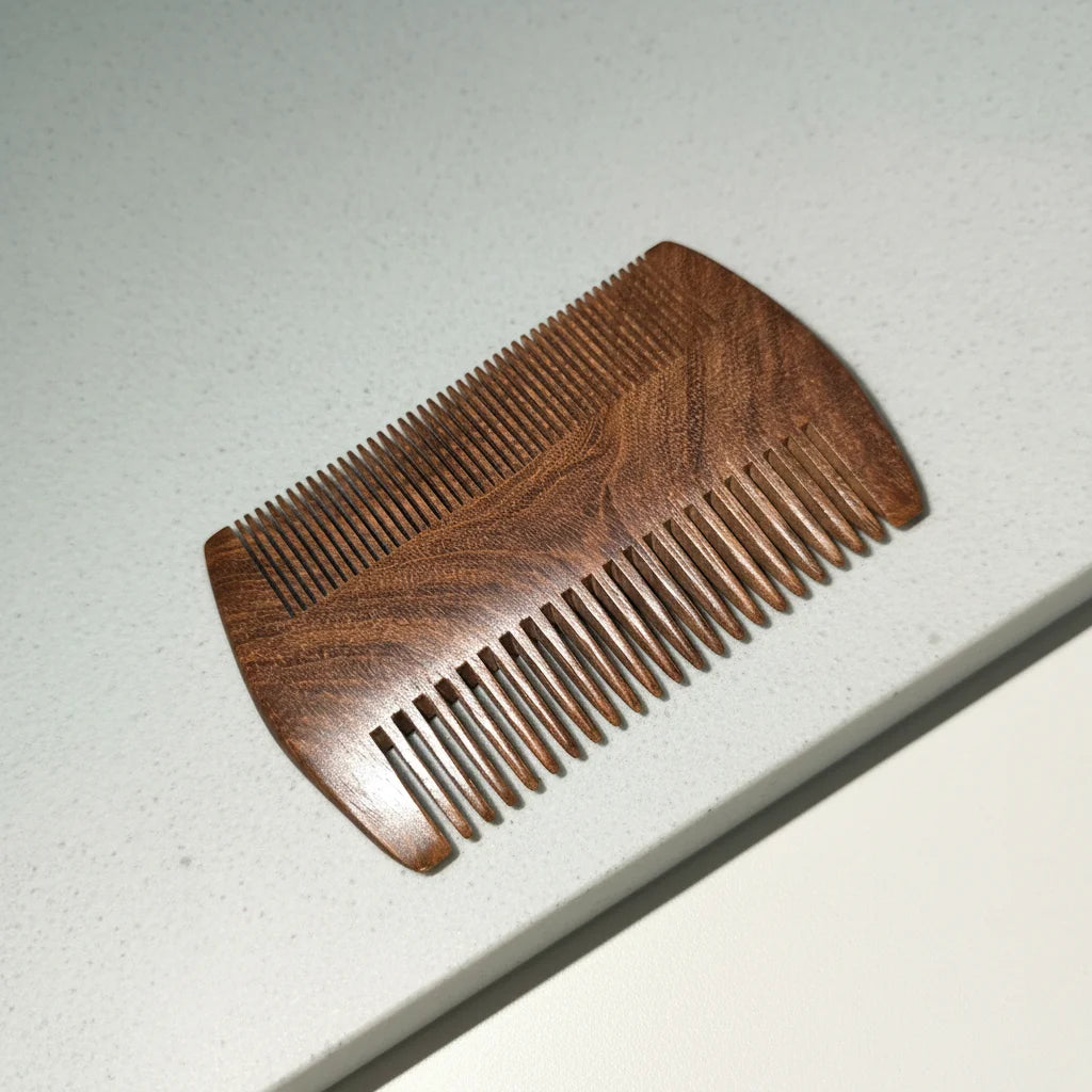Rosewood beard comb with fine and wide teeth on light stone surface