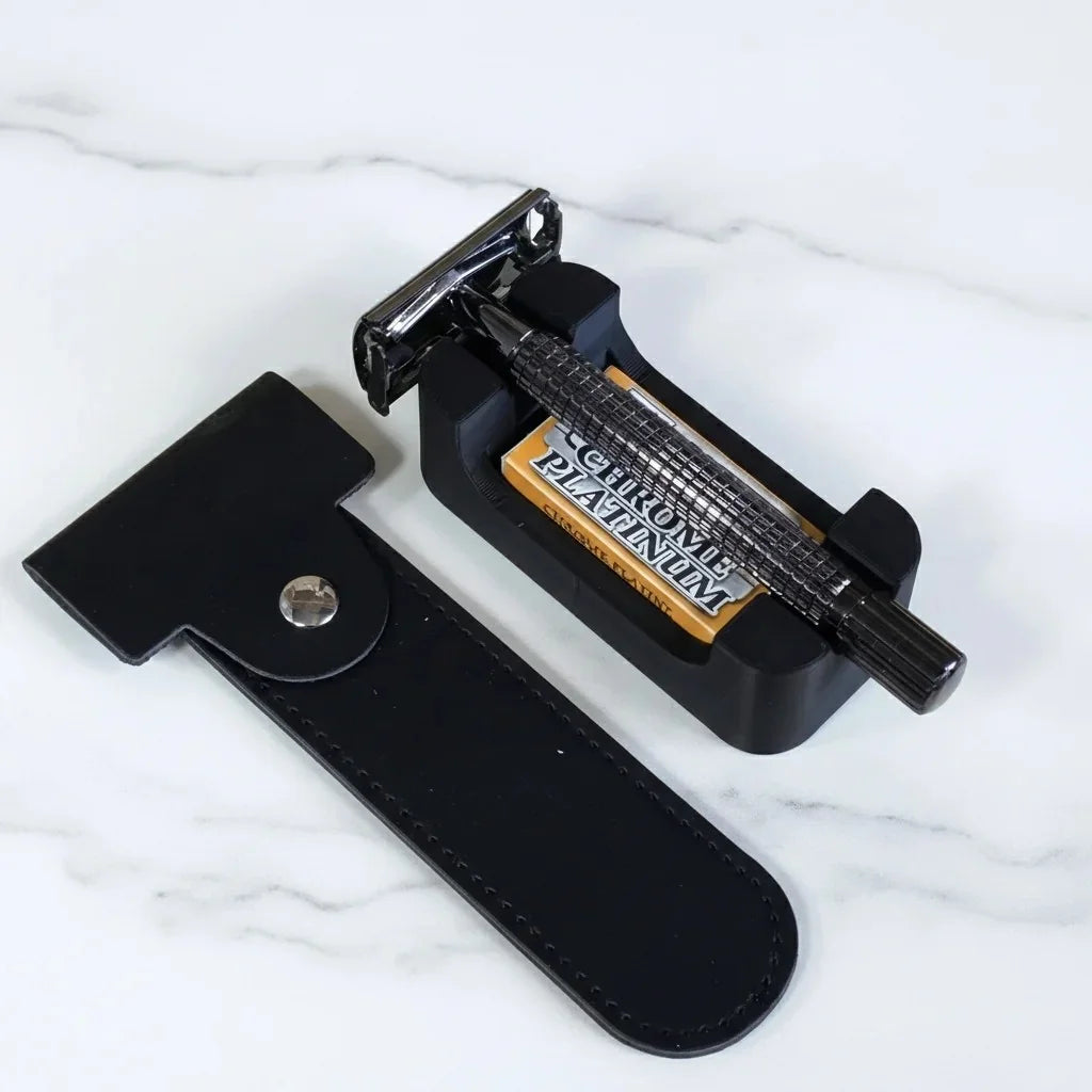 Black chrome-plated double-edge safety razor with textured grip, leather pouch, stand, and platinum blades