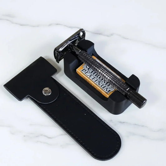Black chrome-plated double-edge safety razor with textured grip, leather pouch, stand, and platinum blades