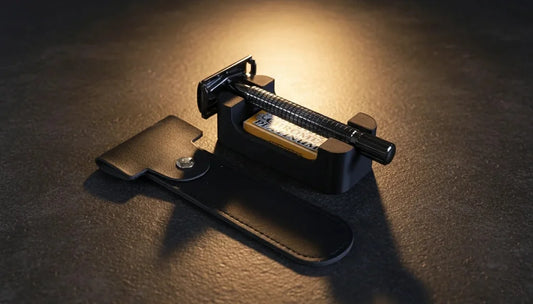 Gunmetal black double-edge safety razor with knurled handle resting on a dark leather snap-closure travel case
